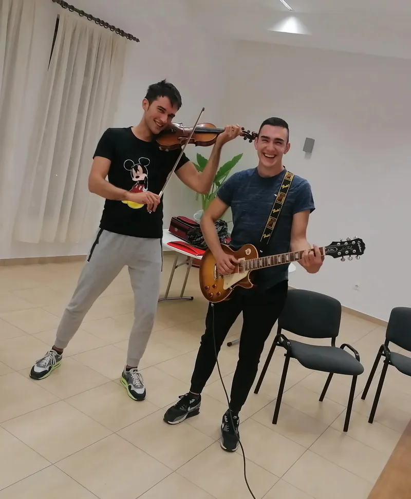 Učitelj gitare svira električnu gitaru s violinistom